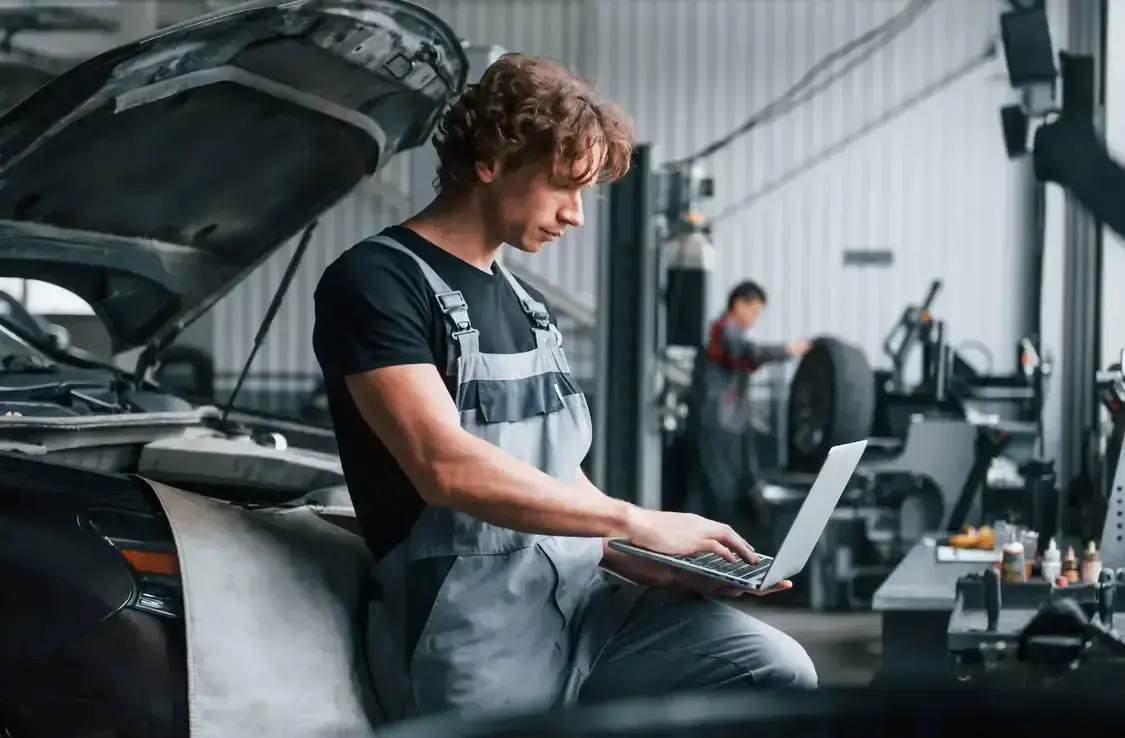 Man looking at laptop fixing a car